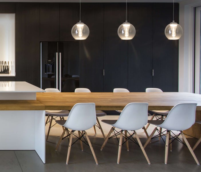 Esszimmer mit großem Holztisch, weißen Stühlen und drei runden Pendelleuchten