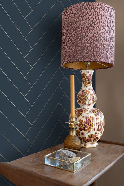 Dekorative Szene mit Lampe, Kerze und geometrischer Tapete für Wohnraumgestaltung.