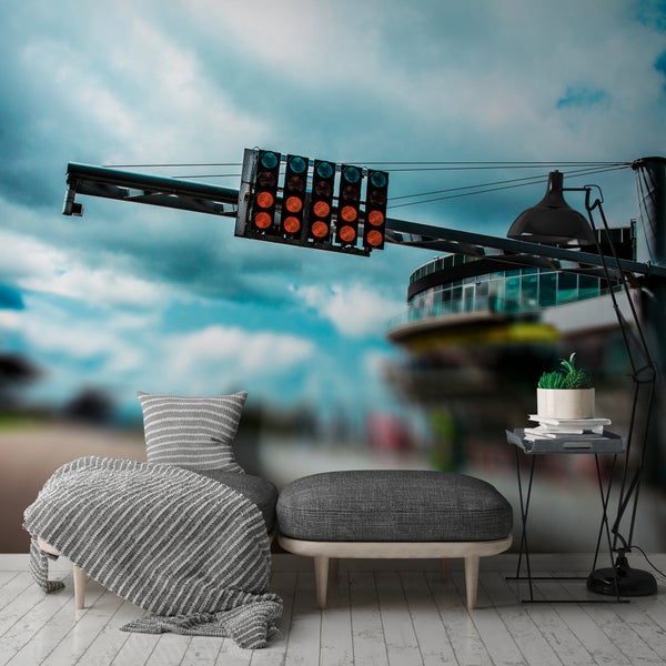 Vliesfototapete mit Motorsportmotiv, Startampel an einer Rennstrecke unter bewölktem Himmel, in einem modern eingerichteten Zimmer mit grauer Sitzbank.