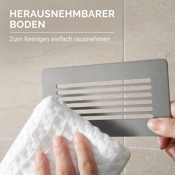 Herausnehmbarer Boden einer Duschablage wird zur Reinigung mit einem Tuch abgewischt.