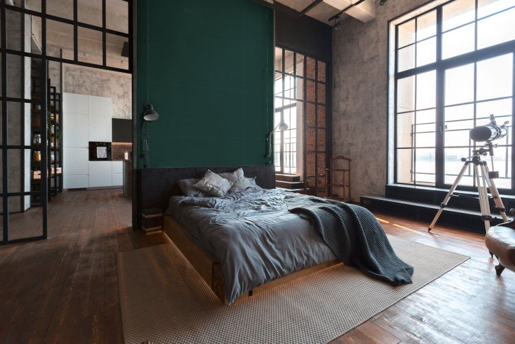 Schlafzimmer im Loft-Stil mit Bett, Teppich und großen Fenstern