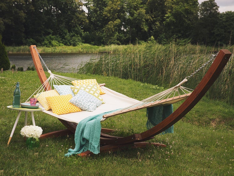 Holzhängematte mit Kissen und Decke im Garten am See