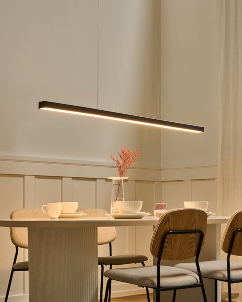 Moderne schwarze LED-Pendelleuchte in einem hellen Esszimmer über einem weißen Esstisch mit Holzstühlen und Gedeck.