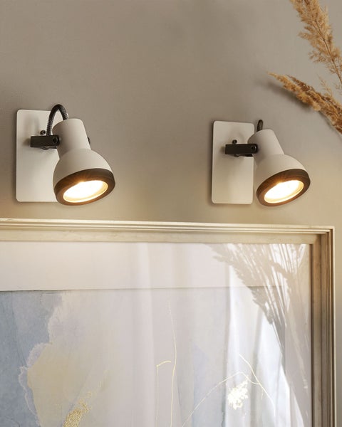 Zwei verstellbare Wandspots in Weiß und Schwarz, montiert über einem Bild. Modernes Design mit schwenkbarem Leuchtenkopf.