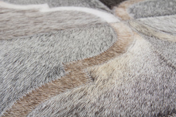 Nahaufnahme eines Patchwork-Teppichs aus Rindsleder mit natürlichem Haar und sichtbaren Nähten.