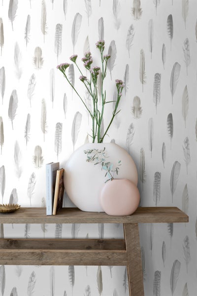 Dekoratives Interieur mit Federn Tapete, Büchern und Vasen auf einem Holztisch