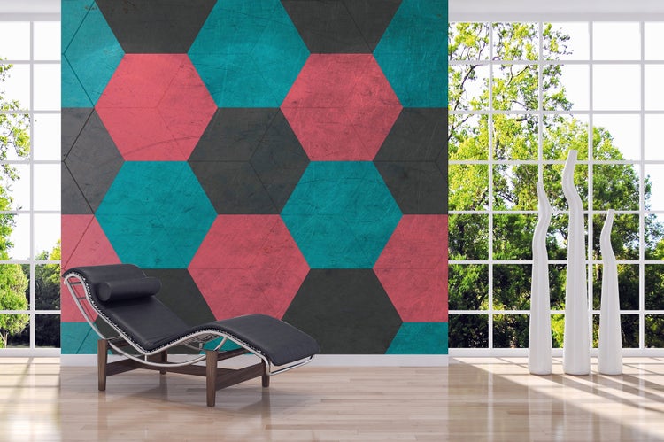 Vliestapete mit Sechseckmuster in Blaugrün, Rosa und Grau in einem hellen Wohnzimmer mit Design-Liege, Holzboden und großen Fenstern.
