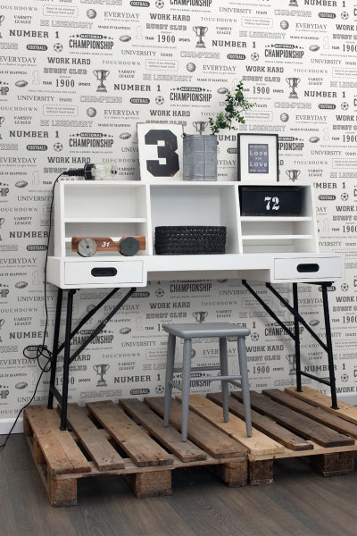 Dekoratives Arbeitszimmer mit Schreibtisch, Ablageflächen und Hocker auf einer Holzpalette vor einer Motivtapete