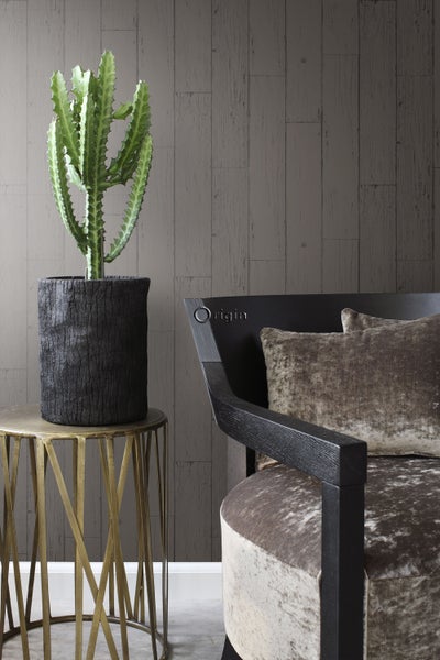 Dekorative Innenszene mit Kaktus in schwarzem Topf auf einem Beistelltisch, neben einem Sessel und einer grauen Holzpaneelwand