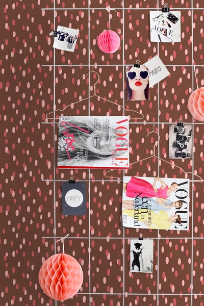 Dekorative Wand mit Magazinen und Fotos an einem Drahtgitter befestigt