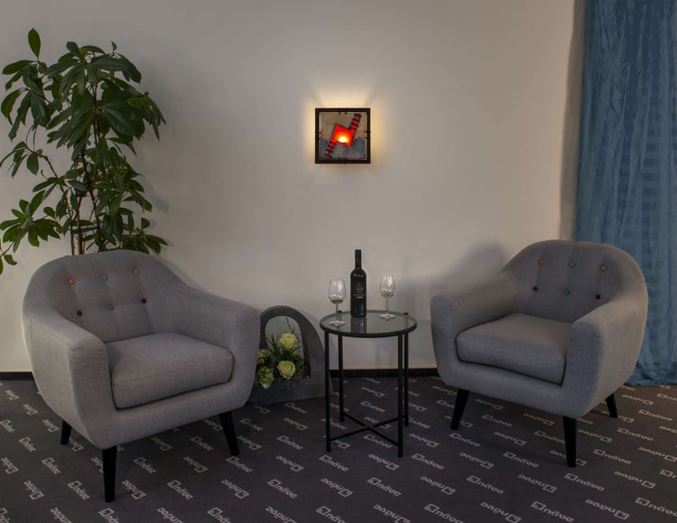 Wohnzimmerambiente mit zwei Sesseln, einem Tisch mit Wein und Gläsern sowie einer Wandleuchte.