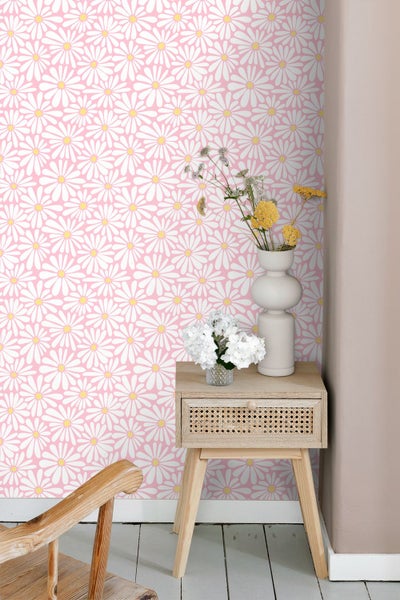 Rosa Tapete mit Gänseblümchenmuster in einem hellen Raum mit Blumenvasen und einem Holzbeistelltisch.