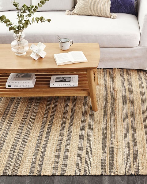 Gestreifter Jute-Teppich in einem hellen Wohnzimmer mit hölzernem Couchtisch und Sofa.