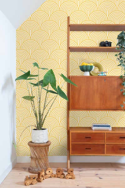 Szene mit Regalmöbeln, Zimmerpflanze und geometrischer Tapete