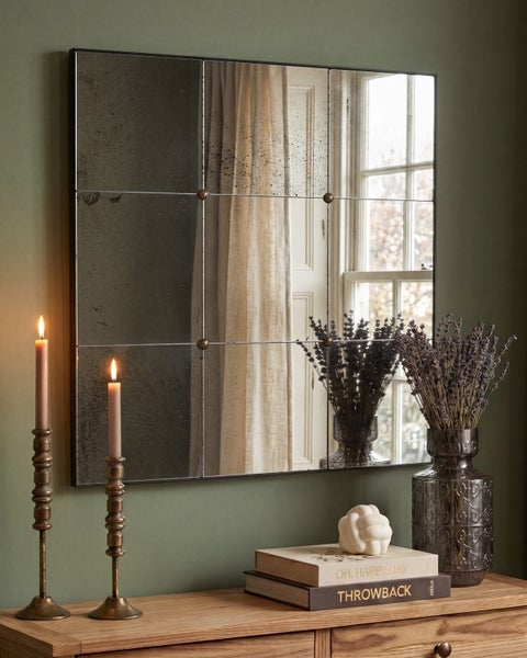 Rechteckiger Wandspiegel im Fensterdesign mit antikem Effekt, aufgehängt über einer Holzkonsole mit Kerzen und Lavendel.