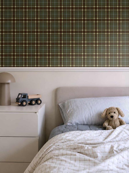 Kinderzimmer mit grün-braun karierter Tapete im Tartan-Muster, weißer Kommode mit Spielzeug-Lastwagen und Bett mit Stofftier.