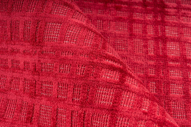 Nahaufnahme eines roten Teppichs mit strukturiertem Karomuster und umgeschlagener Kante.