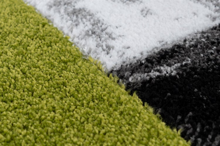 Nahaufnahme eines weichen Hochflor-Teppichs mit verschiedenen Farbfeldern und dichter Struktur.