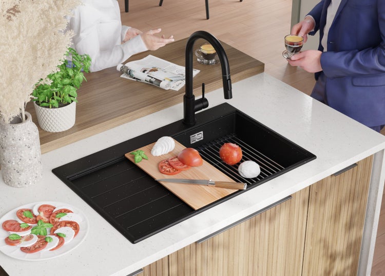 Schwarzes Spülbecken mit Abtropffläche, Armatur und Lebensmitteln auf einer Küchentheke.