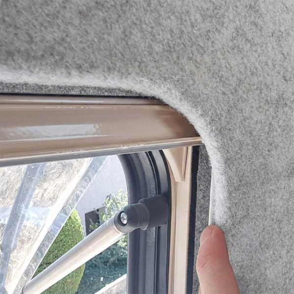 Detailansicht eines Fahrzeugfensters mit grauer Innenverkleidung und Ausstellmechanismus