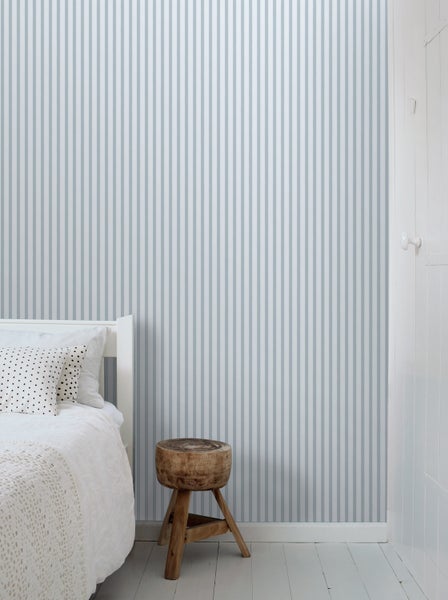 Raum mit gestreifter Tapete, Bett und Hocker