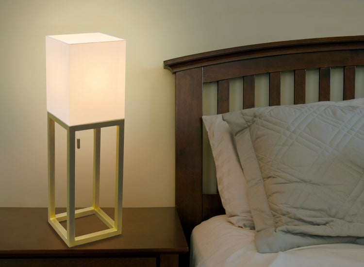 Nachttischlampe mit quadratischem Schirm neben einem Bett.