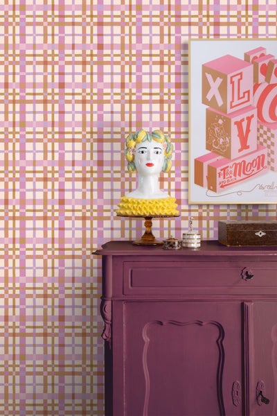 Vliestapete mit handgezeichnetem Karomuster in Rosa und Braun hinter einer lila Kommode mit dekorativer Büste.