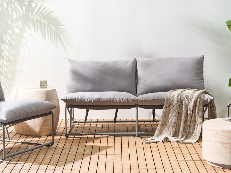 Szene mit einer grauen Gartenbank, einem Beistelltisch aus Stein und einem Überwurf