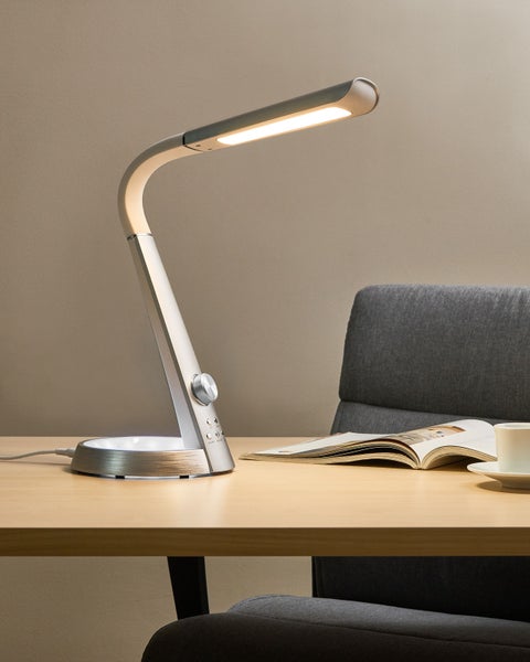 Schreibtisch mit LED-Tischleuchte, Buch und Kaffeetasse