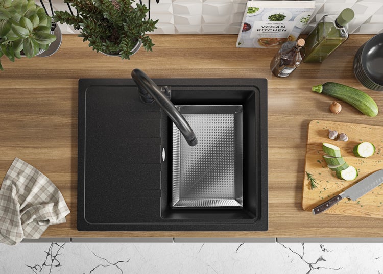 Spültisch aus Granit mit Abtropfschale und Armatur auf einer Küchentheke mit Lebensmitteln