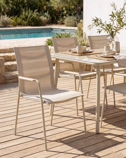 Moderne Garten-Essgruppe auf einer Holzterrasse am Pool, bestehend aus Armlehnenstühlen mit Netzbespannung und einem rechteckigen Tisch.