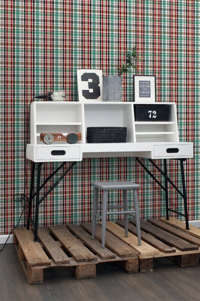 Dekorativer Schreibtisch mit Ablagefächern und Hocker auf einer Holzpalette vor einer karierten Tapete.