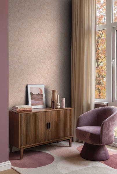 Vliestapete mit fächerförmigem Muster in einem hellen Wohnzimmer mit Holz-Sideboard, Sessel und Vorhängen.