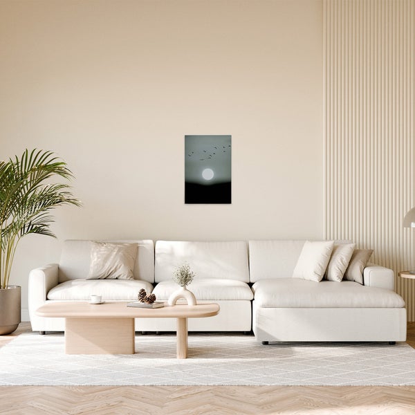 Wohnzimmer mit Couch und einem Wandbild mit Vogelsilhouette und Sonne