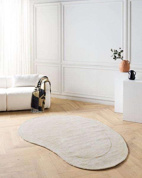 Beige, organischer Teppich in einem hellen Wohnzimmer mit Sofa
