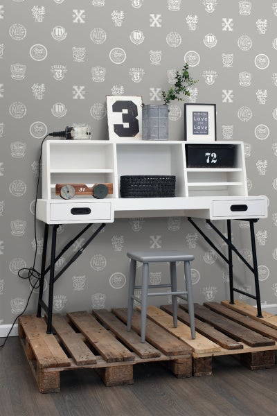 Arbeitszimmer mit weißem Schreibtisch, Ablagefächern und grauem Hocker auf Holzpaletten