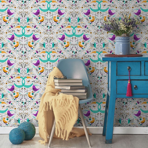 Szene mit floraler Vogelmuster-Tapete, blauem Beistelltisch und Stuhl mit Decke und Büchern