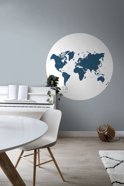 Raumansicht mit Weltkarte als Wanddeko, weißem Klavier, Esstisch und Designlampe