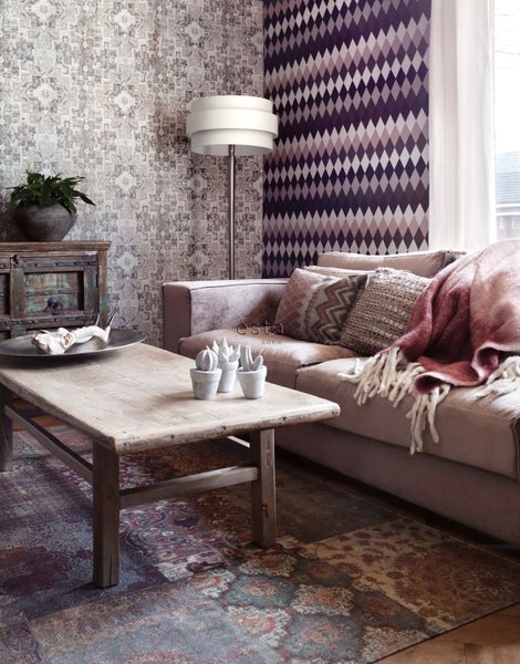 Wohnzimmer mit Sofa, Holztisch und gemusterten Tapeten für eine gemütliche Atmosphäre