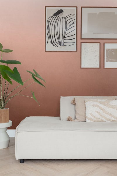 Wohnzimmer mit Sofa, Kissen, Pflanzen und Wandbildern