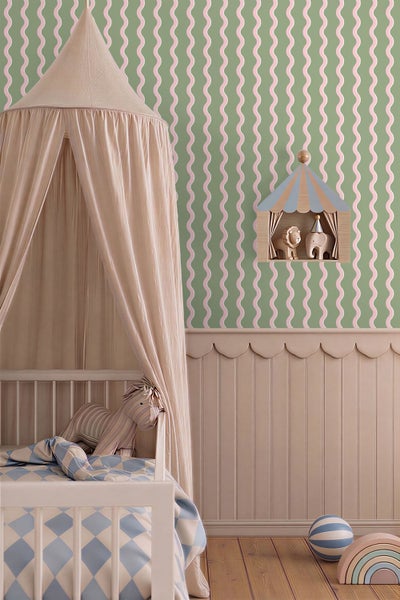 Tapete mit vertikalem Wellenmuster in Grün und Rosa im Kinderzimmer über einer Wandverkleidung neben einem Gitterbett mit Betthimmel.