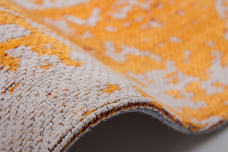 Nahaufnahme eines gewebten Teppichs in Orange und Grau mit Fokus auf Struktur, Muster und Kante.
