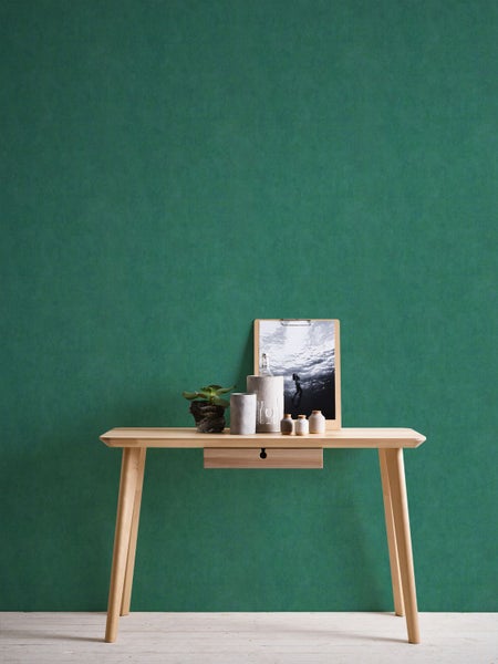 Wohnraum mit grüner Wandtapete, Futon und Kissen.