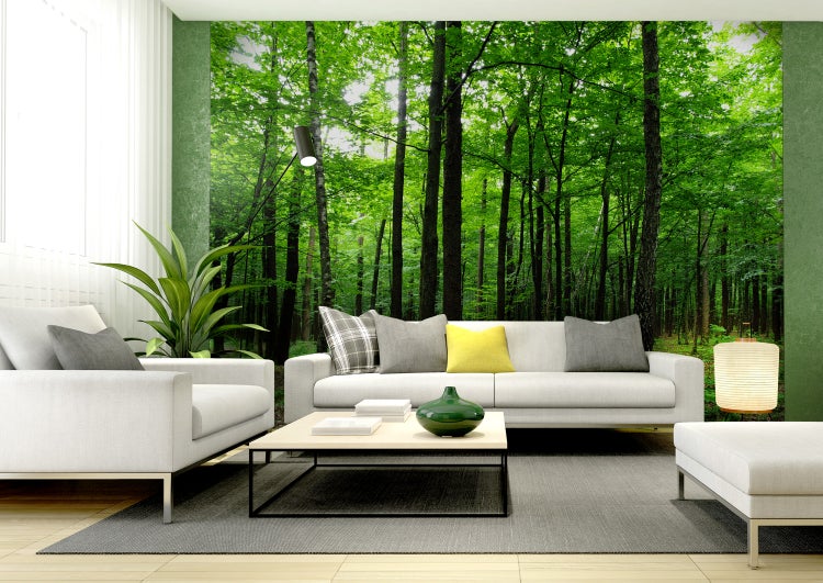 Helles Wohnzimmer mit Fototapete, die einen grünen Wald darstellt, und weißen Möbeln.