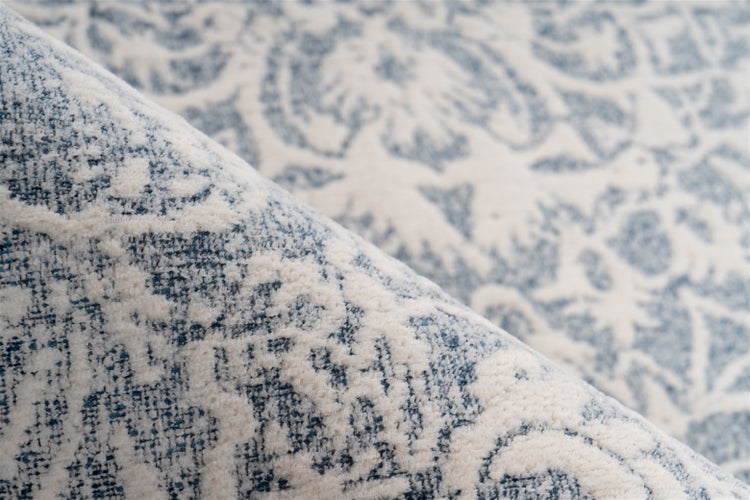 Nahaufnahme eines Teppichs mit Ornamenten und gewebter Oberflächenstruktur.