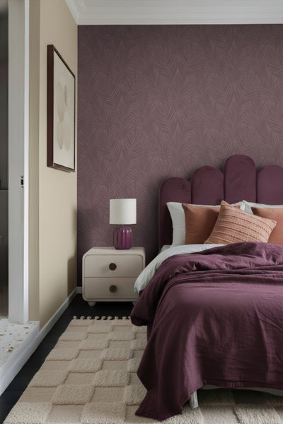 Schlafzimmer mit Bett, Nachttisch, Lampe und gemusterter Tapete