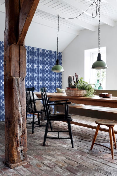 Esszimmer mit Holztisch, Stühlen, blau gemusterter Tapete und Hängelampen