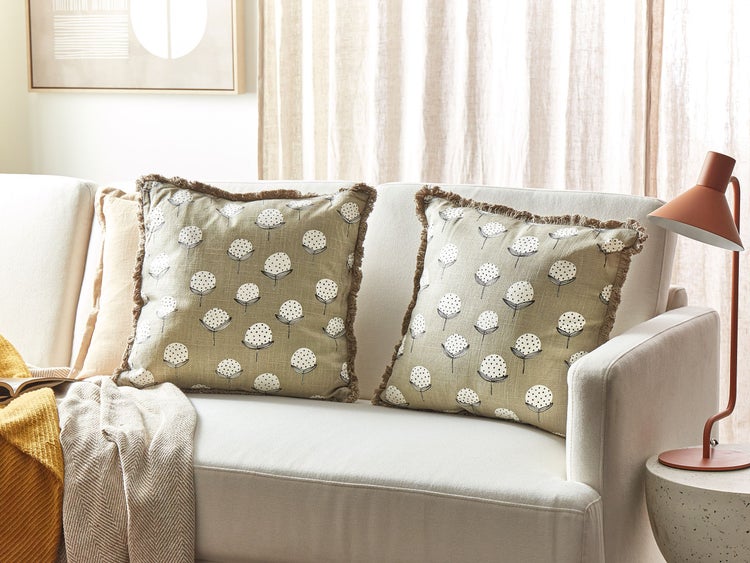 Dekorative Kissen mit Blumenmuster und Fransen auf einem Sofa