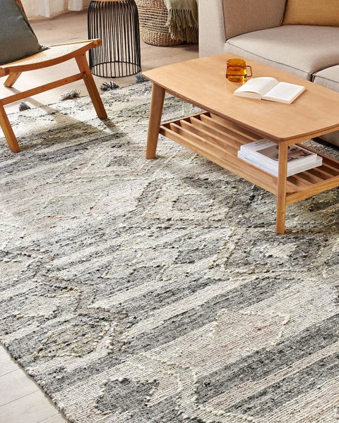 Wohnzimmer mit Sofa, Kommode, Zimmerpflanze und gemustertem Teppich