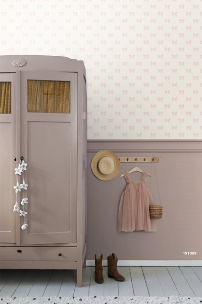 Tapete mit Schleifenmuster im Kinderzimmer, kombiniert mit einer Wandverkleidung und einem klassischen Kleiderschrank aus Holz.